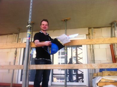 Bauleiter mit Plänen und Helm auf einer Baustelle